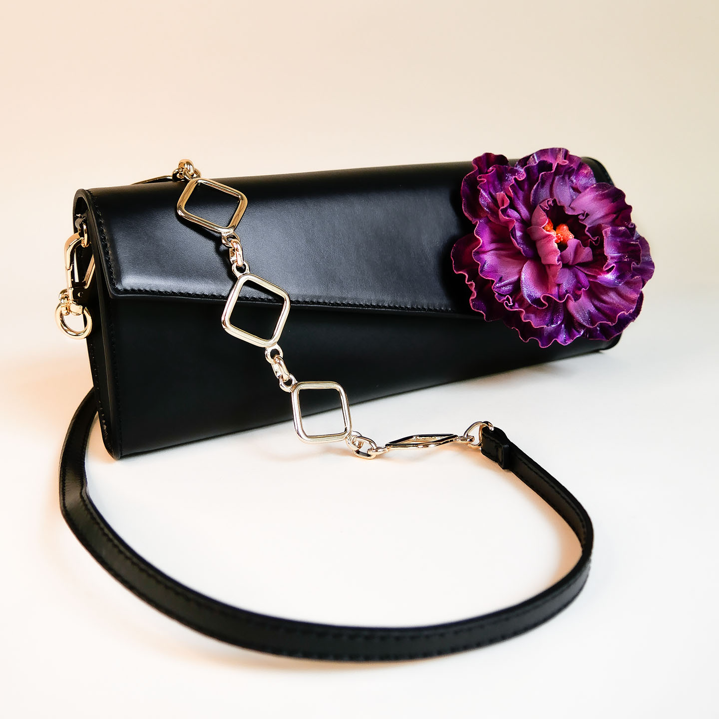 Abendtasche aus Leder schwarz Frontansicht mit Tragegurt und lila Blume