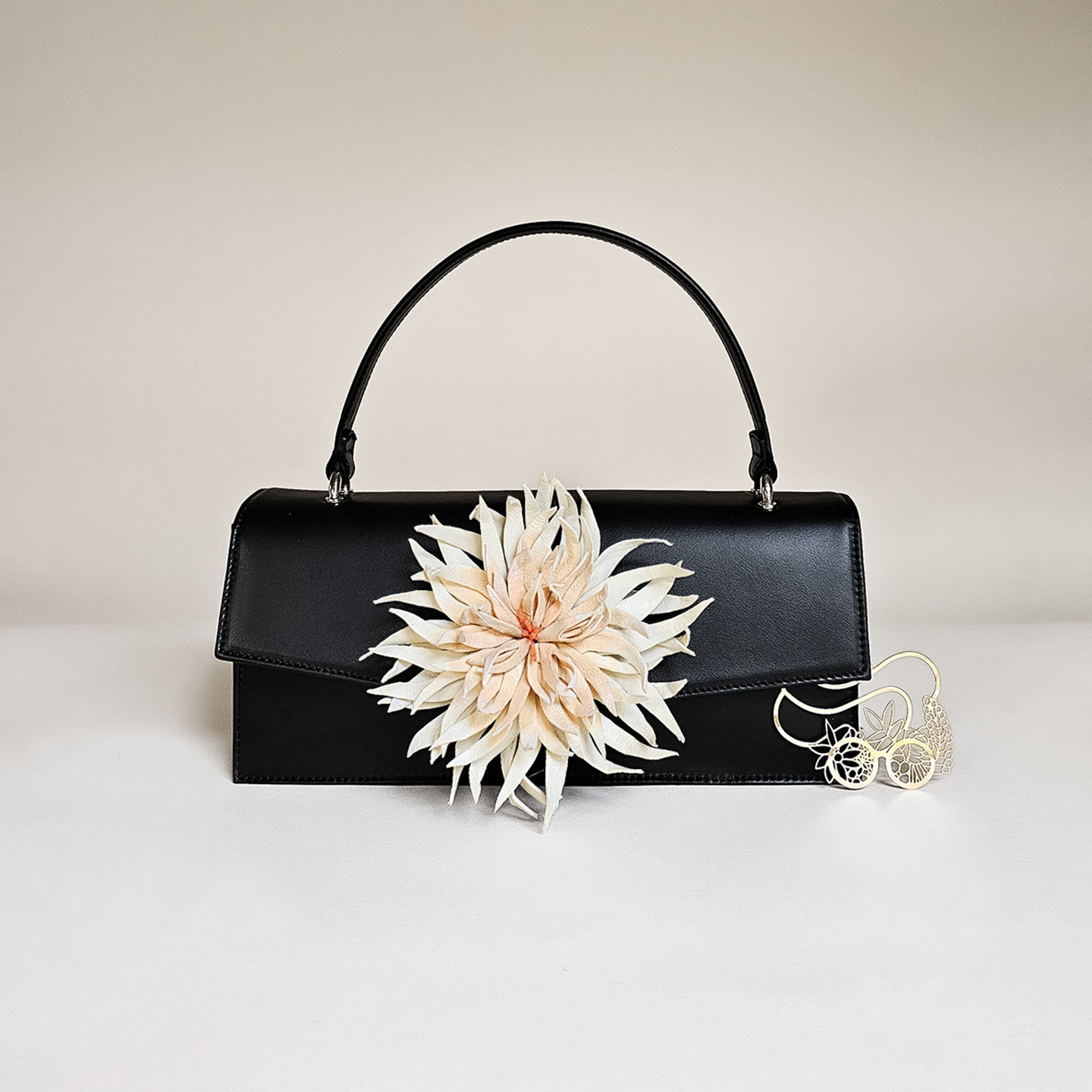 Klassische Handtasche aus schwarzem Leder mit cremefarbener Dahlienblüte