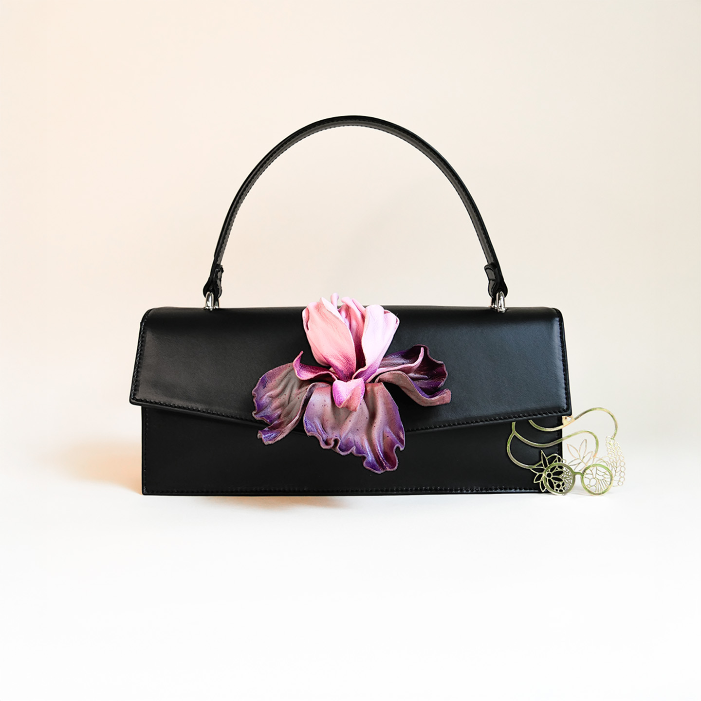 Klassische Handtasche aus schwarzem Leder mit lila Irisblüte