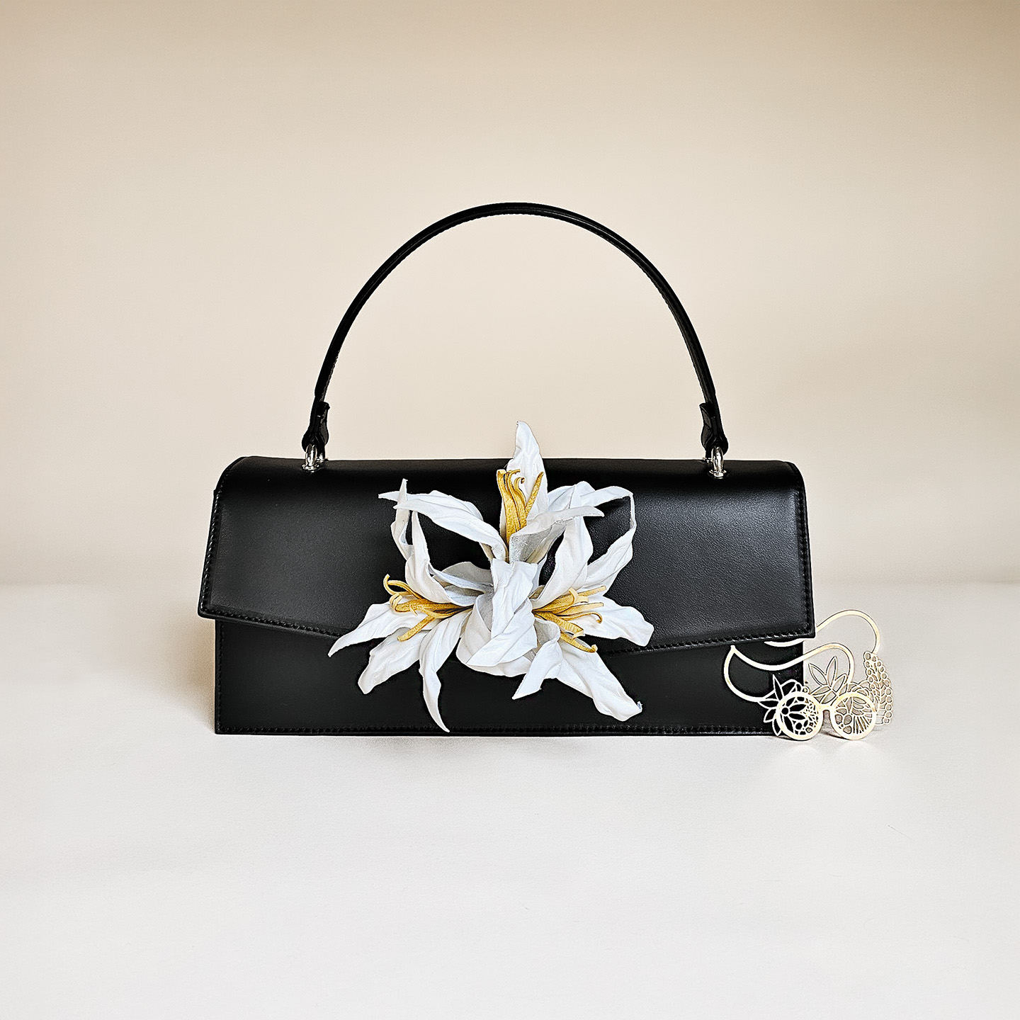 Klassische Handtasche aus schwarzem Leder mit Lilien-Blume in weiß