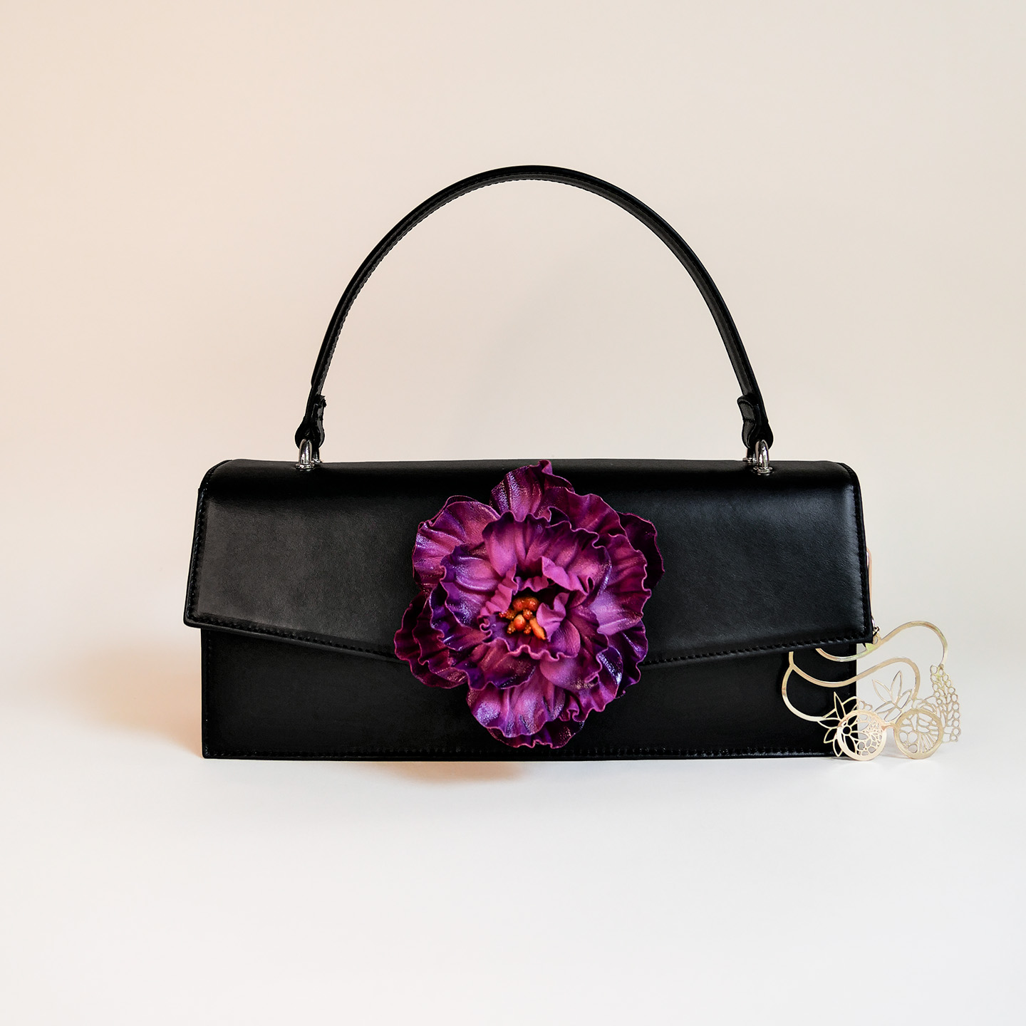 Klassische Handtasche aus schwarzem Leder mit Blume in lila