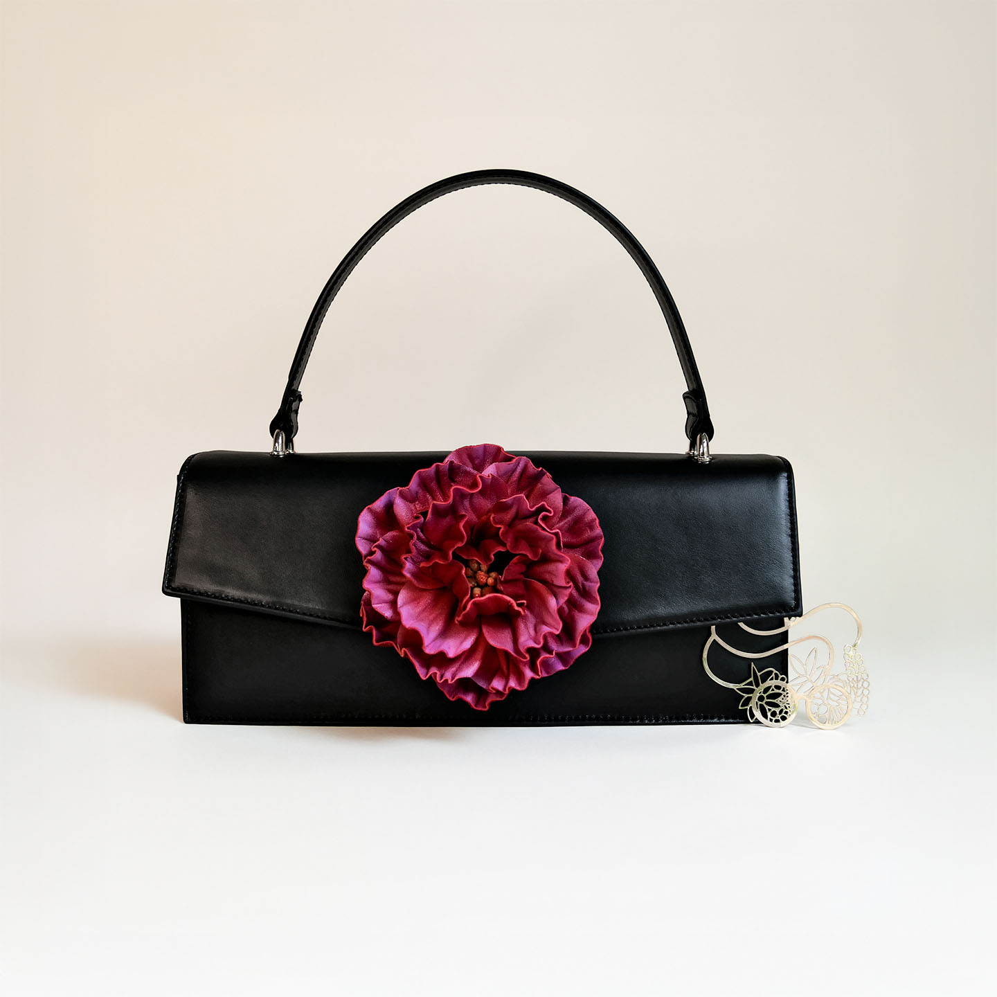 Klassische Handtasche aus schwarzem Leder mit pinker Pfingstrose
