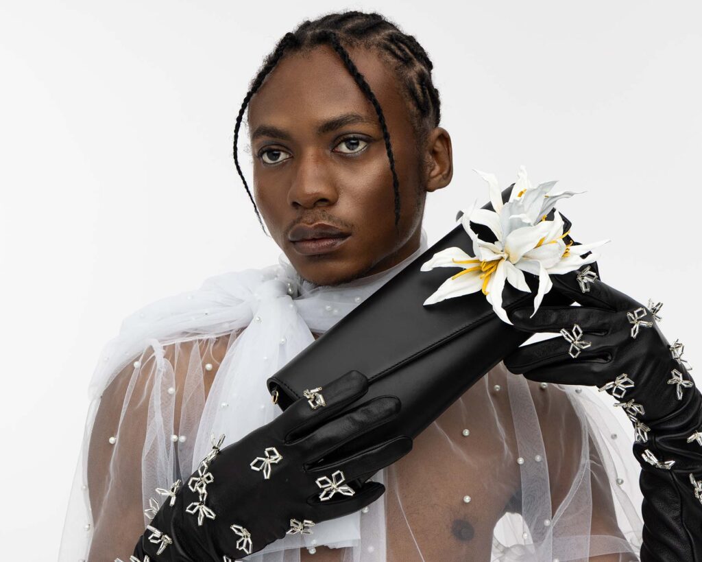 Clutch Tasche aus schwarzem Leder mit ansteckbarer weißer Lilie aus Leder, getragen von POC-Model