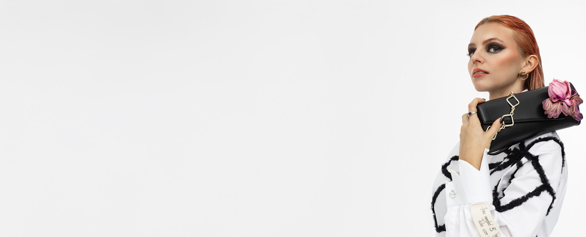 Abendtasche Posy aus schwarzem Leder mit lila Irisblume, getragen von Model