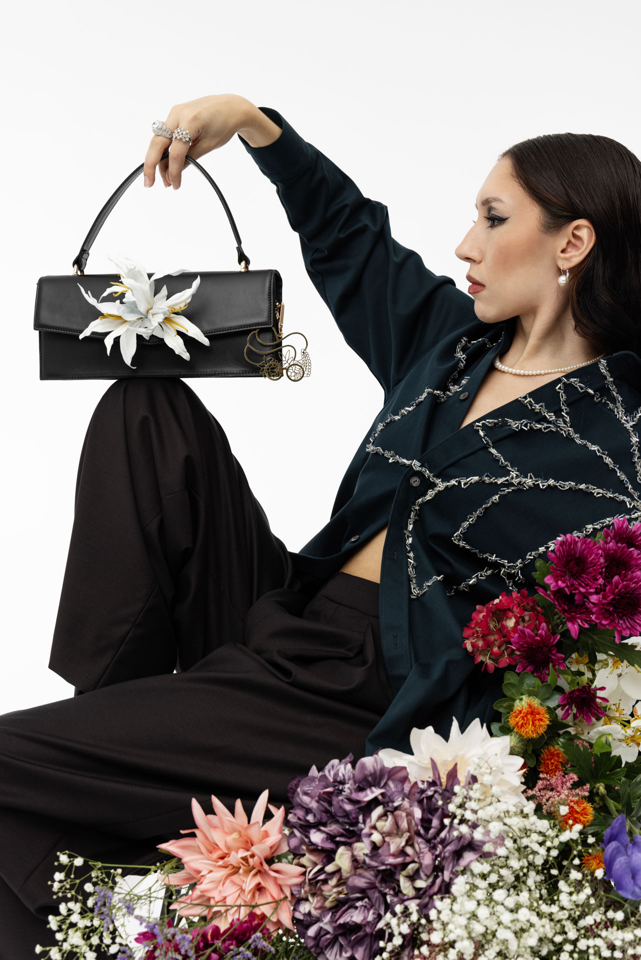 Exklusive Lederhandtasche Modell "Gaia" in schwarz mit Blume aus Leder "Lily", gehalten von Model in Blumenmeer