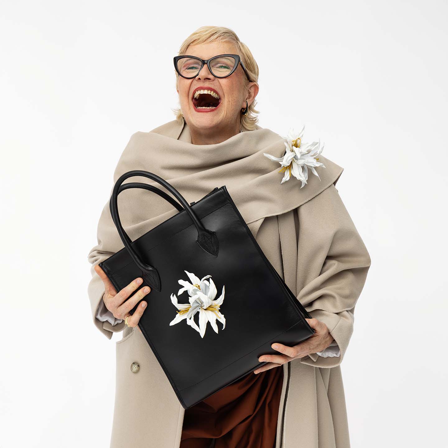 Shopper aus Leder mit abnehmbarer Lederblume in Lilienform in weiß, Nahaufnahme mit lachendem Model