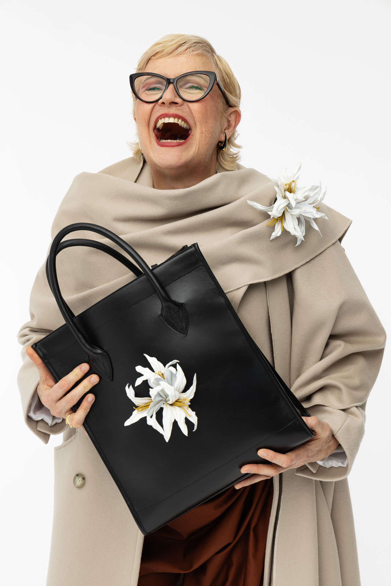 Shopper Tasche aus nachhaltigem schwarzem Leder mit weißer Lederblume, Nahaufnahme mit lachendem Model