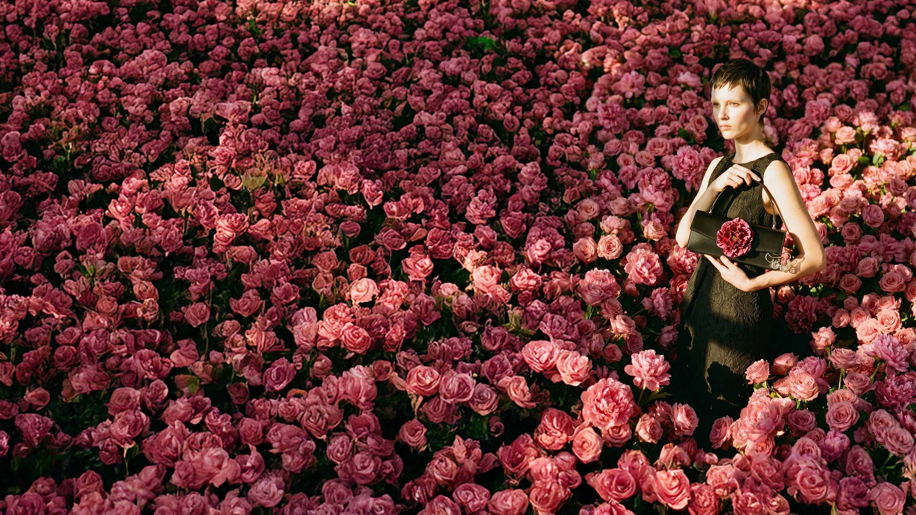 Handtasche mit Blume pink, getragen von Model in Blumenfeld